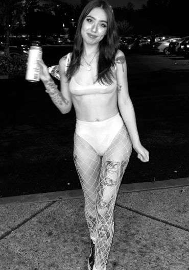 Young woman posing outdoors at night in a daring outfit.
