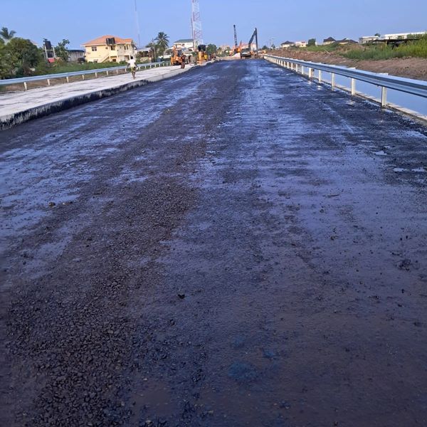 A newly paved road under construction with machinery in the distance.