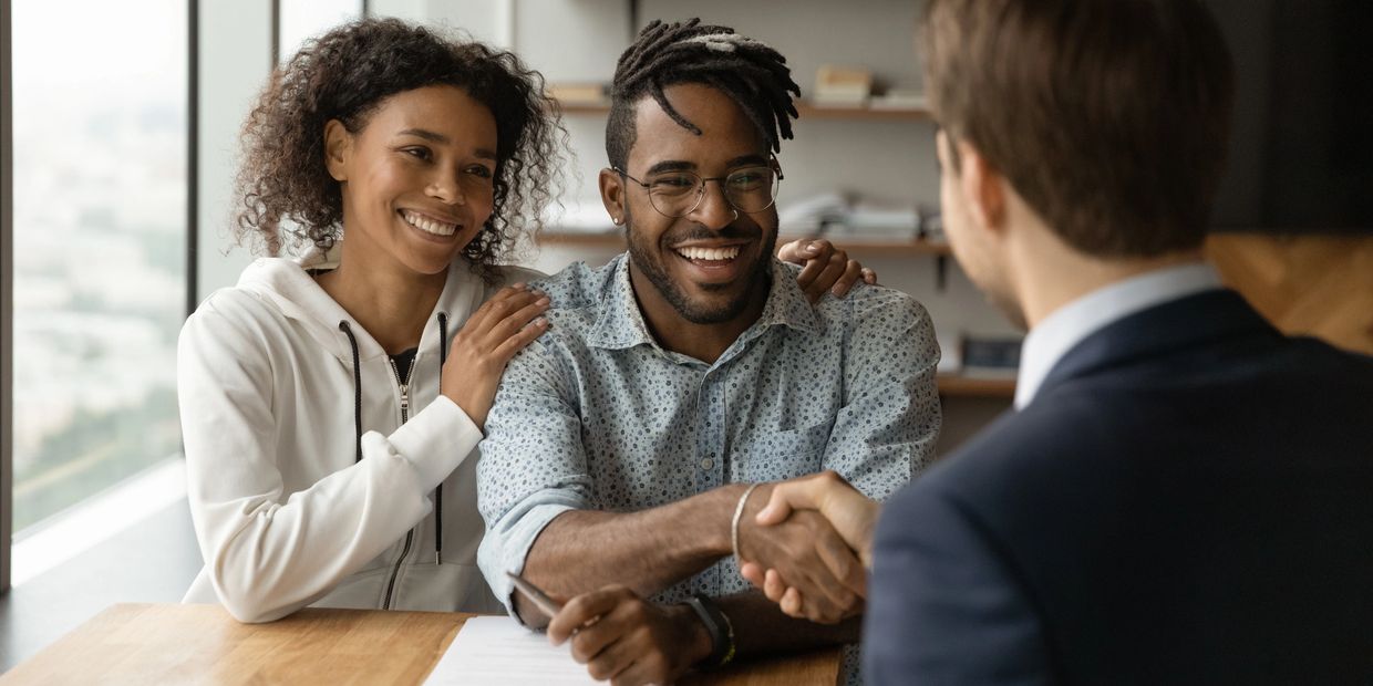 Happy couple shaking hands with a professional in an office setting.