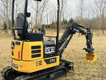 Yellow John Deere 17G mini excavator parked on dry grass.