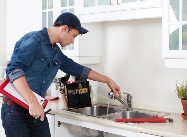 Plumber inspecting kitchen sink faucet.
