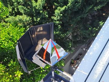 A solar cooker with a reflective pyramid design outdoors in sunlight.