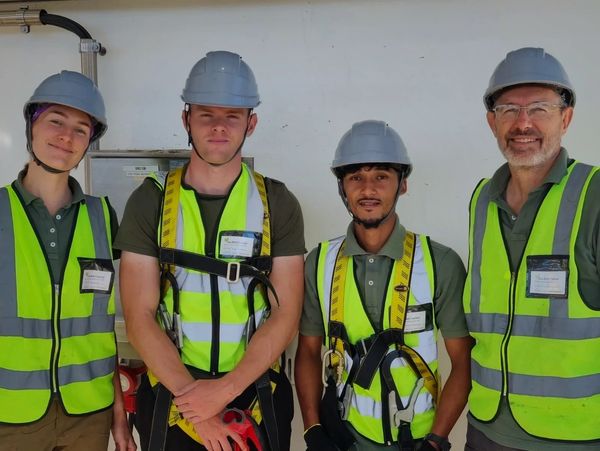 Four construction workers wearing safety helmets and reflective vests.