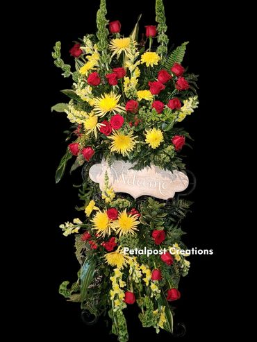 Large "Welcome" sign on easel designed with fresh flowers, red roses and yellow spider mums.