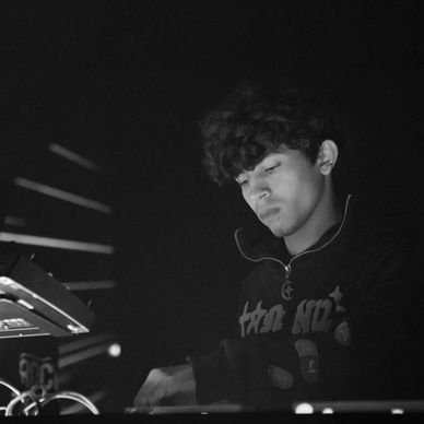 Young DJ intensely mixing music in a dimly lit setting.
