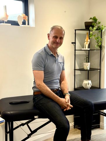 Man sitting on a massage table in a clinic room.
