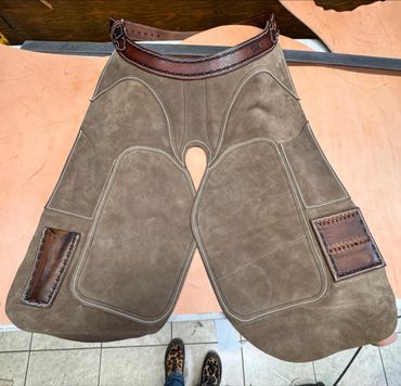 Handcrafted leather chaps with reinforced stitching and brown accents.