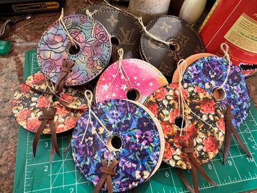 Colorful round leather pieces with floral and star patterns on a cutting mat.