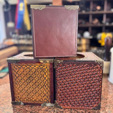 Three intricately designed leather boxes with metal corner accents.