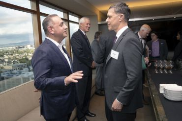Two men in suits conversing at a business event.