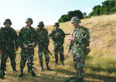 Soldiers in camouflage gear standing on a field.