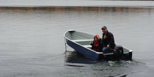 A man and child in a small motorboat on calm water.