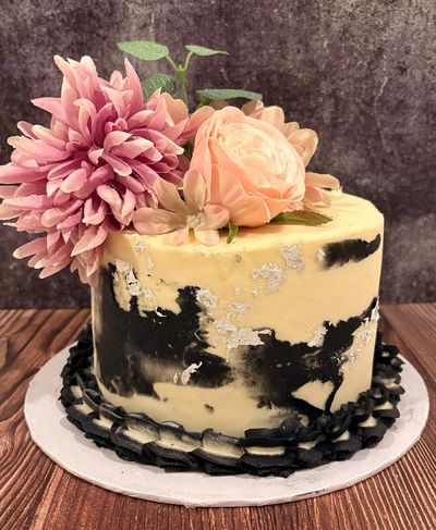Elegant black and cream cake with pink flowers.