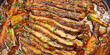 Sliced cooked meat with vegetables in sauce.
