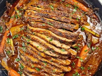 Slices of cooked ribs in sauce with carrots and herbs.