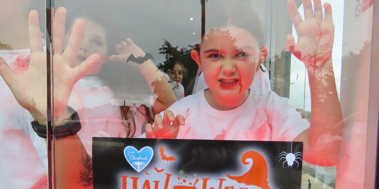 Children in Halloween costumes behind glass window.