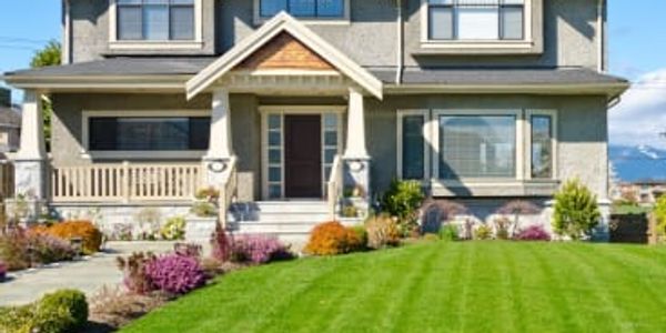 A large, modern two-story house with a manicured front lawn.