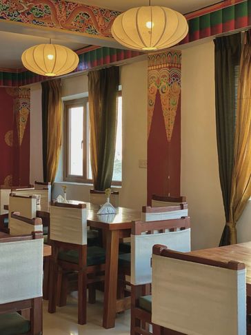 Elegant dining area with wooden chairs and soft lighting in a traditionally decorated room.