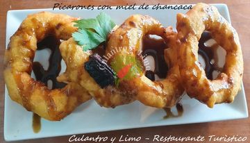Picarones drizzled with chancaca syrup on a white plate.