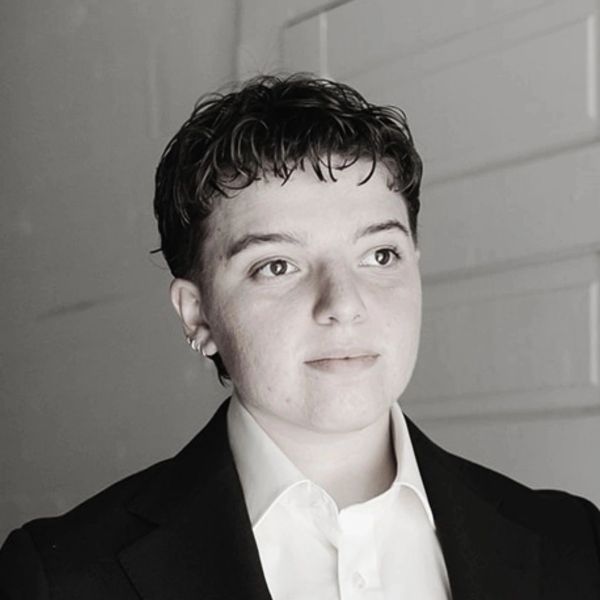 Young person in a suit looking to the side.