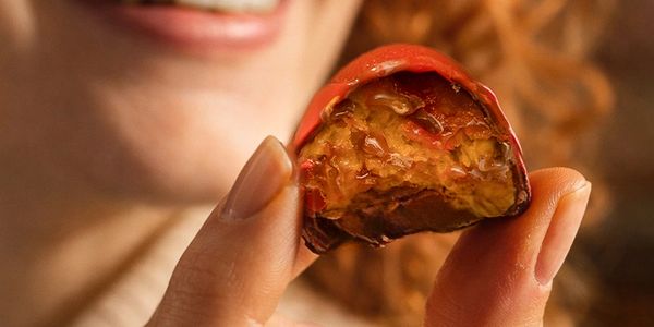 Close-up of a person holding a bitten-red chocolate.