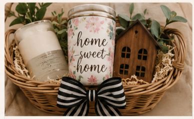 Cozy gift basket with candles, wooden house, and decorative bow.