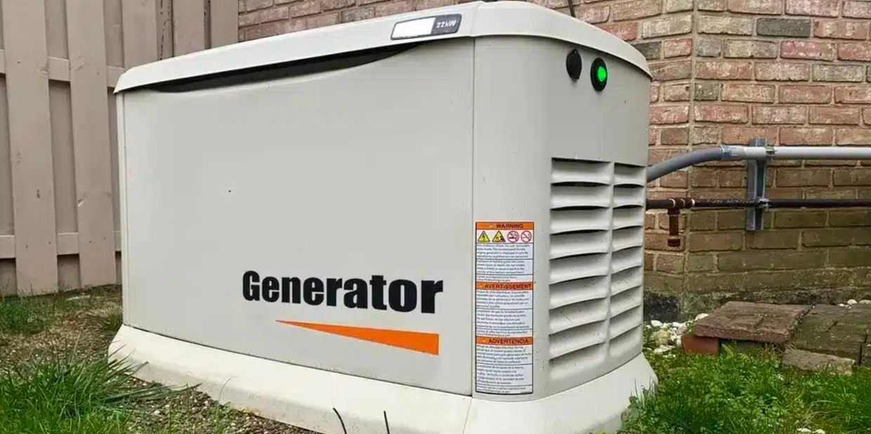 Outdoor standby generator with green indicator light beside a brick wall.