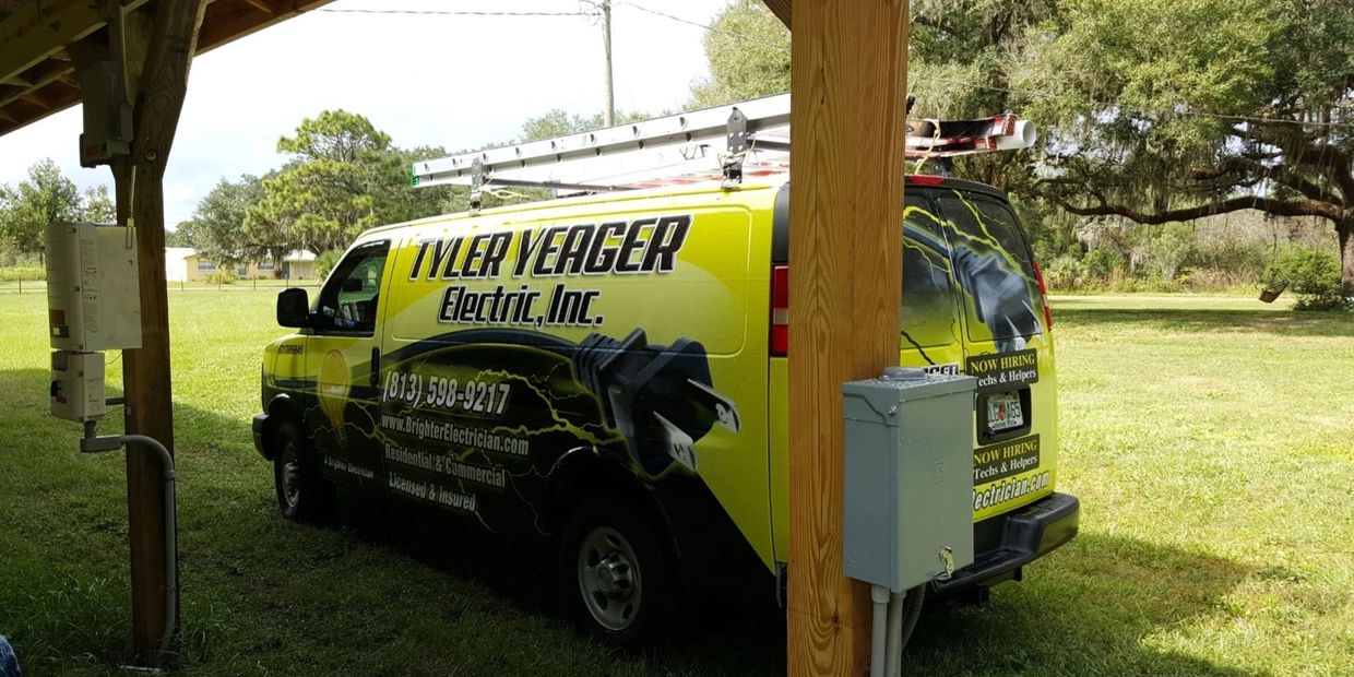 Tyler Yeager Electric van parked under a wooden shelter on a sunny day.