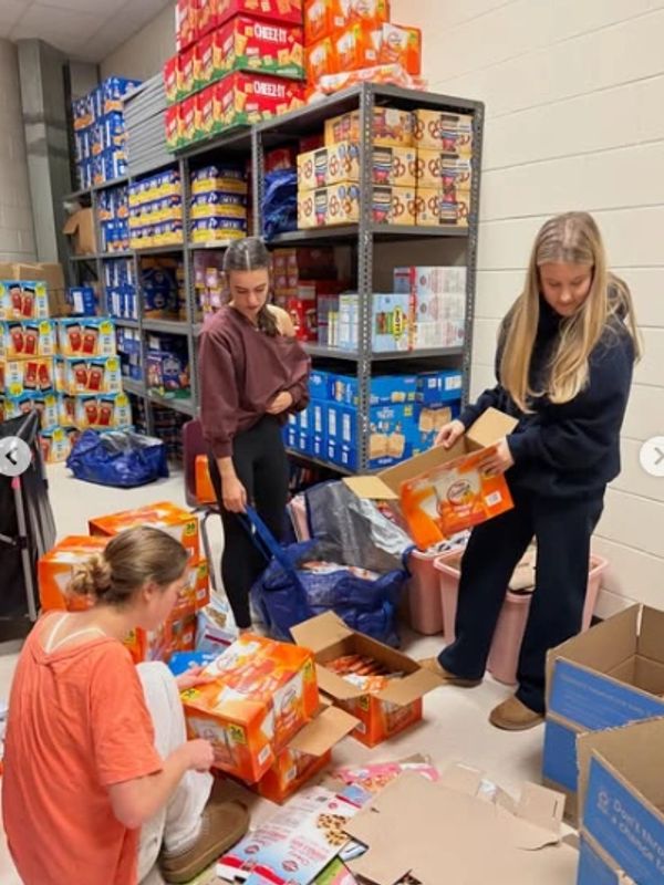 Three women organizing boxes in a storage area.