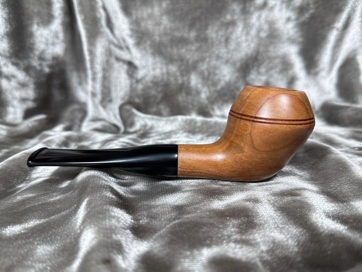 Classic wooden tobacco pipe resting on a silky fabric background.