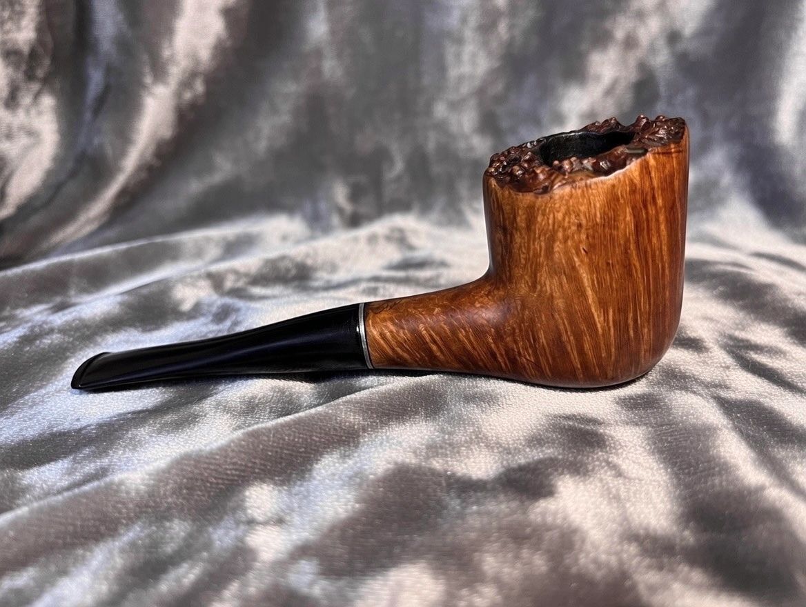 A wooden smoking pipe with a black stem on a textured fabric background.