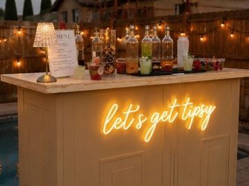 Outdoor bar with neon sign "let's get tipsy".