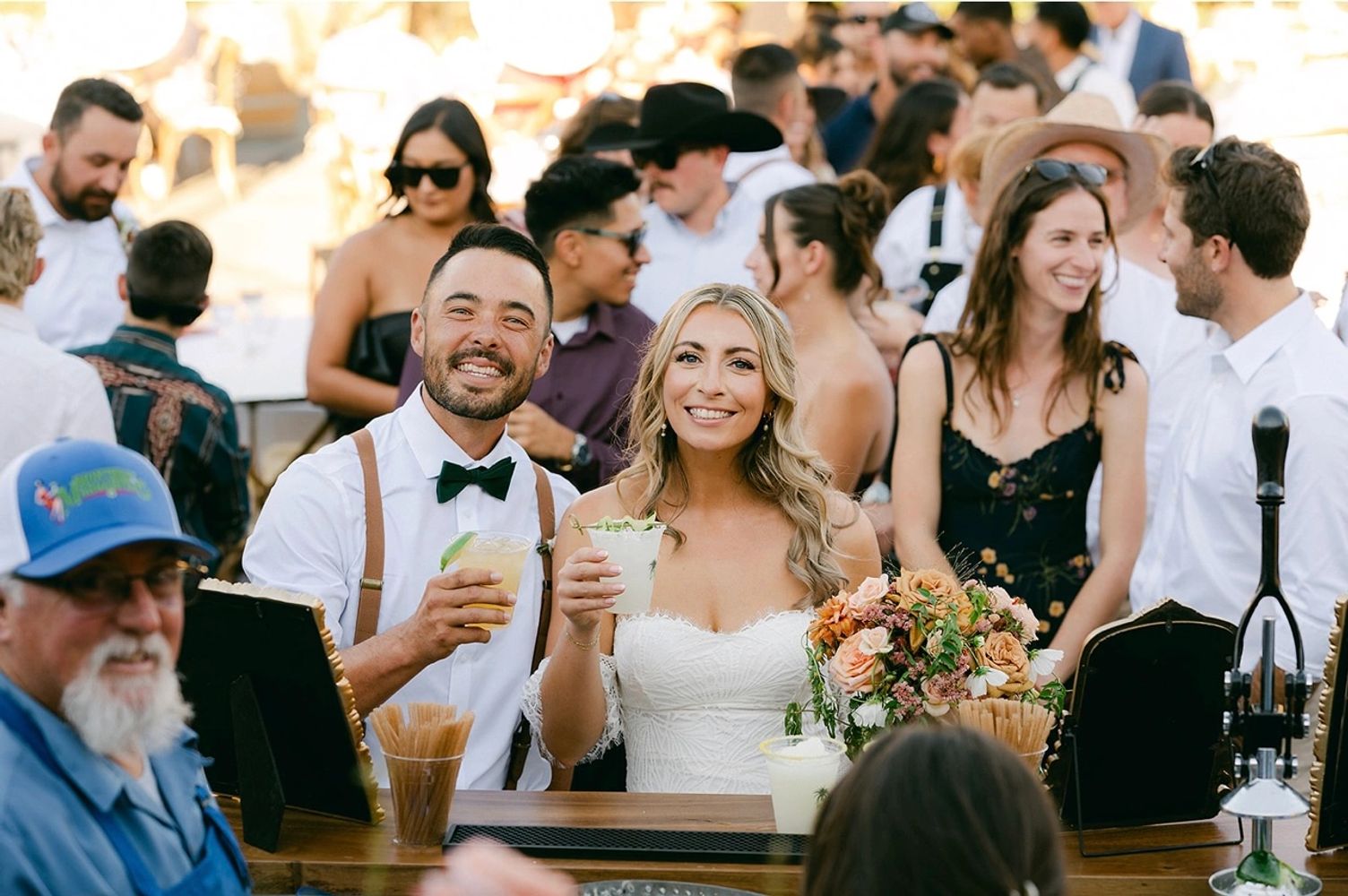 Smiling bride and groom holding drinks at their wedding reception.