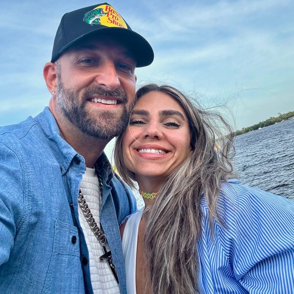 Smiling couple taking a selfie by the water on a sunny day.