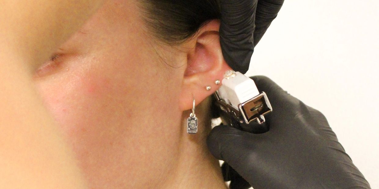 A girl getting her lobes pierced with a gun
