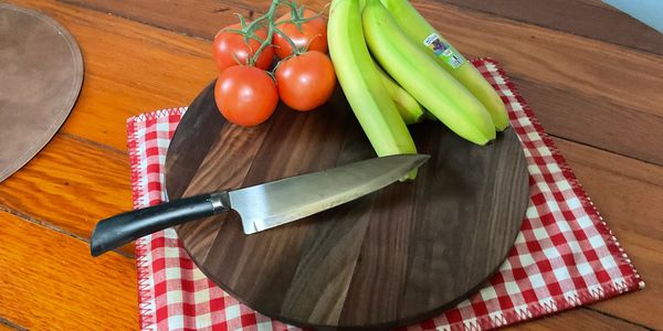 Tomatoes and bananas on a wooden cutting board with a knife.