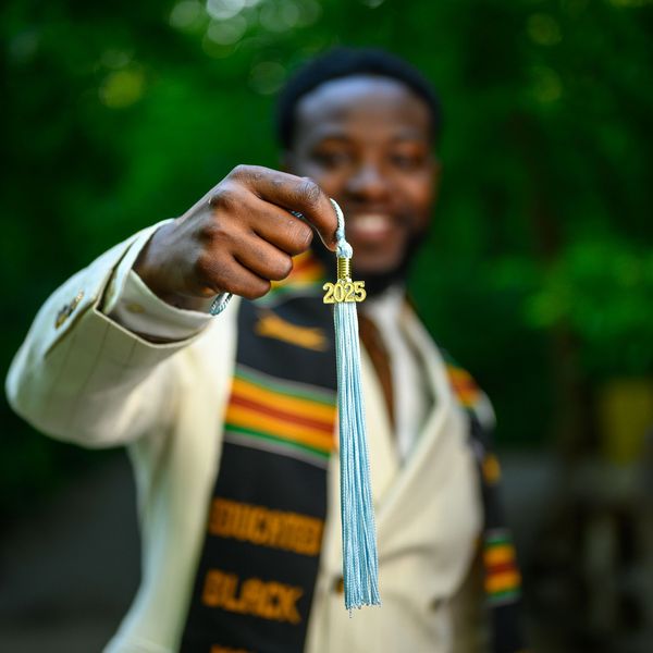 Graduation tassel with 2025 held by a smiling graduate.