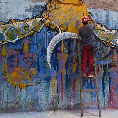 Man painting colorful graffiti on wall.