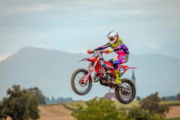 Motocross en plein saut dans un paysage naturel.