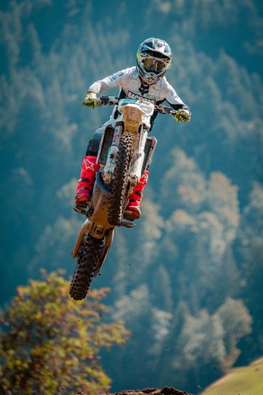 Motociclista pulando em trilha ao ar livre.