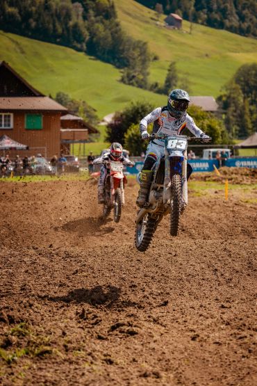 Piloto de motocross saltando em uma pista de terra.