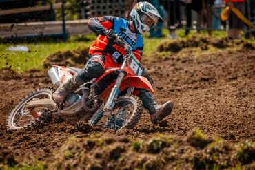 Piloto de motocross em ação na pista de terra.