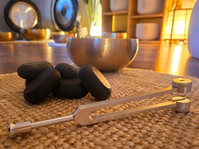 Tuning fork and black stones on a woven mat in a serene room.