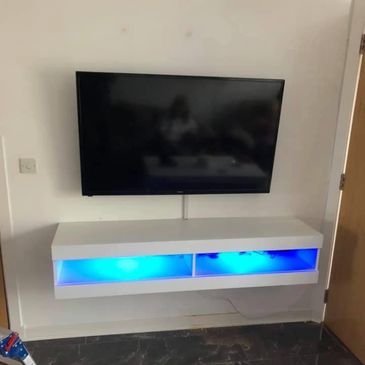 Tv mounted with floating shelf on a plasterboard wall