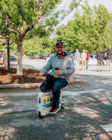 Man riding a small Honda scooter in a park area.