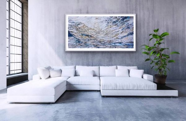 Modern white sectional sofa with ocean-themed artwork above.