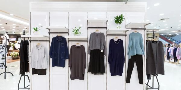 Display of various women's clothing items on hangers in a store.