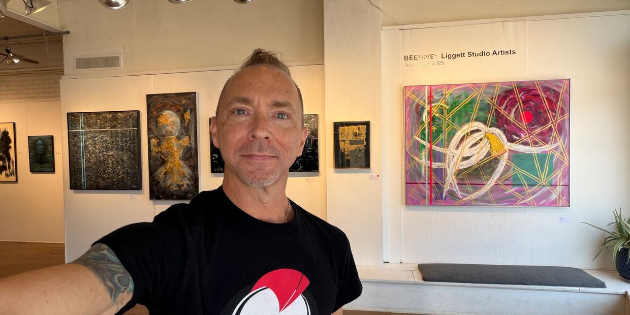 Man taking selfie in art gallery with colorful paintings.