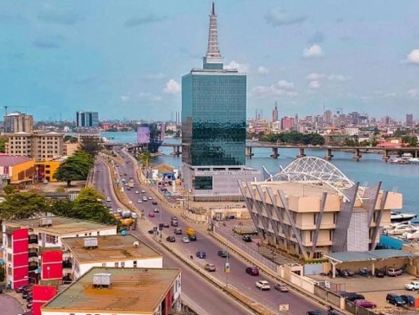 A busy city road with a tall glass building and river nearby.