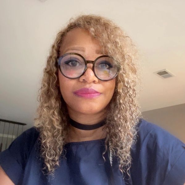 Woman with curly hair and large round glasses.